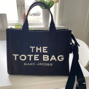 The tote bag från Marc Jacobs - Säljer en svart tote bag från Marc Jacobs. Storlek medium. Köpt i januari 2023, digitalt kvitto finns. Väskan har två handtag och en justerbar axelrem. 