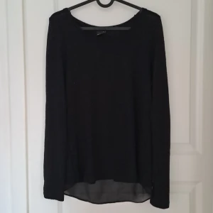 Svart långärmad tröja från Gina Tricot - Säljer en stilren svart långärmad tröja från Gina Tricot. Tröjan har en transparent detalj vid nederkanten som ger en snygg touch. Perfekt för en chic och enkel look. Passar bra till både jeans och kjol.