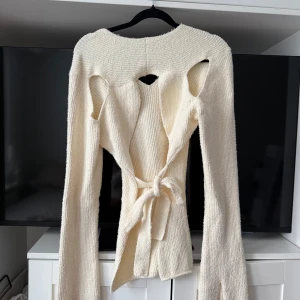 Krämvit stickad omlottkofta med knyt - Superfin krämvit stickad kofta med v-ringning och långa ärmar. Strl L men sitter funkar även på mig som är S/M pga att man kan knyta💛