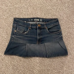 Mörkblå jeanskjol med volang - Snygg mörkblå jeanskjol. Skulle uppskatta att storleken är typ xs-S. Midjemåttet är ungefär 82 cm och längden är  30 cm