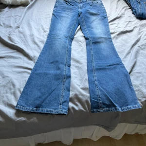 Blå bootcut jeans med utsvängda ben - Säljer ett par klassiska blå jeans med riktigt utsvängda ben och bootcut-modell. Jeansen har normal midja och femficksdesign. Perfekta för dig som gillar retrovibbar och vill sticka ut med en snygg siluett.
