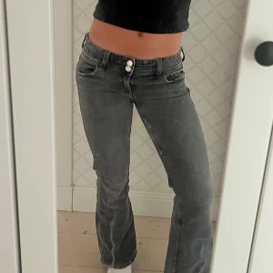 Snygga jeans - Säljer ett par grå jeans med bootcut och låg midja. Jeansen har två knappar framtill, snygga bakfickor med knapp. Köpta från Gina young och är storlek 152, som en xs jag är runt 158-160 och byxorna är i bra skick!💕💕