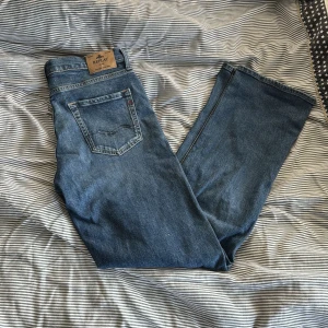 Blå raka jeans från Replay - Snygga blå jeans från Replay i modell THAD med klassisk femficksdesign och raka ben. Jeansen har en mellanblå tvätt och tydliga sömmar, perfekt för en avslappnad och stilren look. Materialet är slitstarkt jeans i bomull.