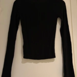 Svart långärmad topp med rund hals - En svart, tight långärmad topp med rundad halsringning. Enkel och stilren design som passar perfekt till jeans eller kjol. Toppens material känns mjukt och följsamt mot kroppen och den har en klassisk, smal passform.