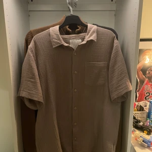 Beige kortärmad skjorta  - Säljer en beige kortärmad skjorta från 157 i mjuk bomull med avslappnad passform. Skjortan har klassisk krage, bröstficka och knäppning framtill. Perfekt för dig som gillar en chill och stilren look. Aldrig använd 