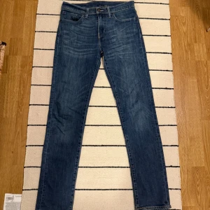 Levi's 511 blå jeans W31 L32 - Säljer ett par klassiska Levi's 511 jeans i blå denim. Modellen är slim fit med raka ben och normal midja. Jeansen har fem fickor, snygga slitningar och den ikoniska Levi's-lappen bak. Perfekta för en avslappnad och stilren look.