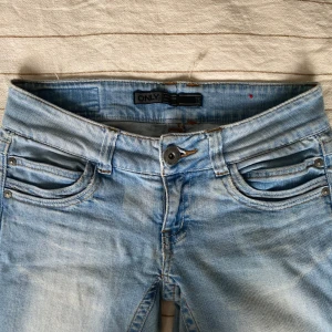 Ljusblå vintage bootcut jeans från ONLY - Snygga ljusblå jeans från ONLY med bootcut-ben och slitna detaljer vid benslut. Klassisk femficksmodell med ljusa tvättade partier och kontrastsömmar. Perfekta för en avslappnad och trendig look. Mått är 34cm rakt över midjan och 75cm innerbenslängd🥰