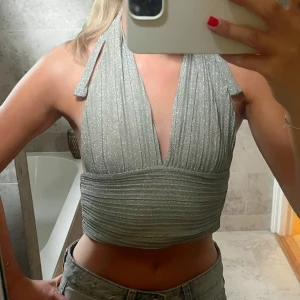 Glittrig guldig halterneck topp - Supersnygg croppad halterneck topp i glittrigt guldtyg. Passar Xs-S då man kan justera axelbanden 