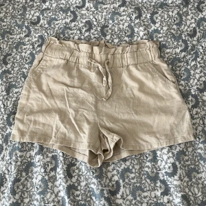 Beige linneshorts med snörning Lindex -  beige linne shorts från Lindex. Med volangkant och justerbar snörning i midjan🩷