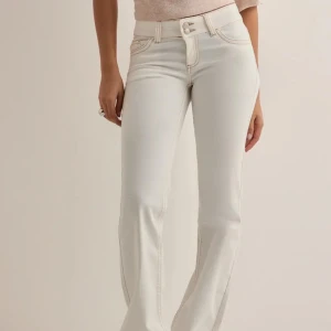 Vita bootcut jeans med kontrastsömmar - Helt oanvända med lappen kvar. Vita jeans från Nelly. Lågmidjade och bootcut i storlek 32. Är för långa för mig men skulle tippa på att de passar någon mellan 160-170. Slutsålda och nytt pris 699. Ställ om ni har minsta fråga eller vill ha fler bilder.