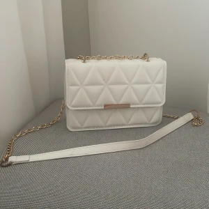 Vit quiltad axelväska med kedja - Snygg vit axelväska med quiltat mönster och guldfärgad kedja.