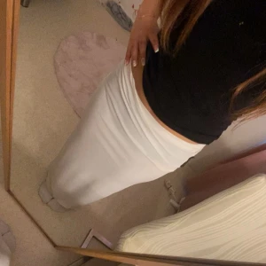 Vit långkjol i tight passform - Säljer en stilren vit långkjol med tight passform. Kjolen är rak i modellen och har en enkel, minimalistisk look som är lätt att matcha med olika toppar. Perfekt för dig som gillar en clean och fräsch stil.