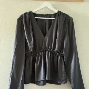 Topp/Blus - En grå satin blus från Gina Tricot i storlek L.