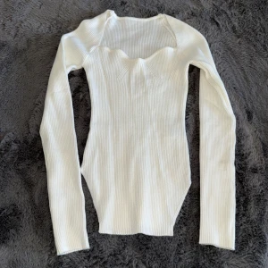 Vit ribbad långärmad tröja - Säljer en vit ribbad långärmad tröja. Tröjan är figurnära och har en snygg, modern look som passar perfekt till jeans eller kjol. Materialet är stretchigt och bekvämt för en skön passform.