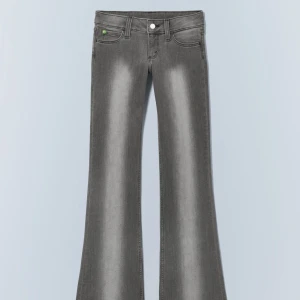 Grå bootcut jeans med låg midja - Säljer ett par grå jeans med snyggt tvättad look och bootcut-ben. Byxorna har låg midja, klassiska fem fickor och en cool faded effekt framtill. Perfekta för dig som gillar en retro vibe och vill sticka ut lite extra.