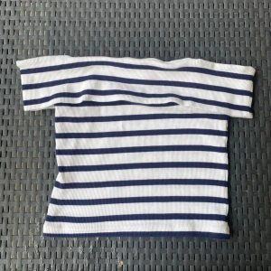 Randig offshoulder topp från H&M - Superfin ribbad offshoulder topp från H&M i vitt med marinblå ränder. Sitter tight och har en croppad passform som ger en fräsch och trendig look. Perfekt till jeans eller kjol för en cool stil. Aldrig använd.