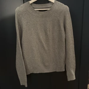 Grå stickad tröja från Vero Moda - Mysig grå stickad tröja från Vero Moda med rund halsringning och ribbade muddar. Perfekt för lager-på-lager och enkel att matcha med jeans eller kjol. Klassisk modell med lång ärm och mjukt material som håller dig varm under kyliga dagar.