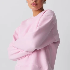 Ljusrosa sweatshirt i bomull - Enkel och snygg ljusrosa sweatshirt med rund hals och långa ärmar. Tröjan har en loose passform och är gjord i mjuk bomull, perfekt för en chill och avslappnad stil.