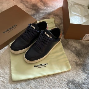 Mörkblå Burberry sneakers i skinn - Burberry skor i mörkblå väldigt fina, mycket bra skick, säljer de för de inte passar mig längre. (KVITTO FRÅN NK INGÅR). (NYPRIS: 6500kr.