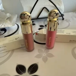 Rare Beauty flytande rouge duo - Två flytande rouge från Rare Beauty med lyxiga guldfärgade lock. Ena nyansen är en mjuk nude-brun och den andra en fräsch rosa. Perfekta för att ge kinderna en naturlig glow och lätt att blenda ut. Snygg design som känns exklusiv i sminkväskan.