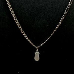 Silverhalsband med droppformad pärla - Stilrent halsband i silverfärg med en kedja och ett hängsmycke i form av en droppformad vit pärla. Kedjan har klassisk länkdesign och pärlan sitter fast med en liten stjärnlik detalj upptill. Perfekt för dig som gillar minimalistiska smycken med en twist.