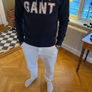 Hoodie från GANT  - Säljer en marinblå hoodie från GANT med vitt tryck på bröstet. Tröjan har bara använts en hadfull gånger. Model är 183cm & 75kg. Bara att skriva om ni har några frågor!
