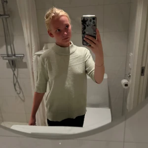 Ljusgrön polotröja med kort ärm - Säljer en ljusgrön polotröja med ribbade muddar och korta ärmar. Tröjan har en avslappnad passform och är stickad i ett mjukt material, perfekt för lager på lager under vår och höst.