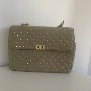 Väska med nitar - Beige väska med guldiga detaljer! Super fin modell, väldigt eftertraktad