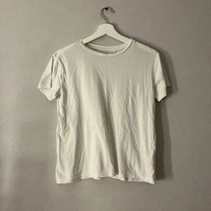 Vit basic t-shirt från 157, storlek S - Enkel och stilren vit t-shirt från 157 i 100% bomull. Klassisk rund halsringning och korta ärmar, perfekt till jeans eller shorts. Modellen är rak och passar dig som gillar en clean och tidlös look.