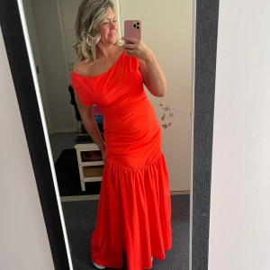 Röd långklänning med oneshoulder - Säljer en superfin röd långklänning med oneshoulder och snygg volang nedtill. Klänningen har en figurnära passform upptill och ett flowigt fall från höften. Perfekt för dig som vill sticka ut med en färgstark look!Helt ny klänning bara tvättad kom aldrig till användning  Storlek L 40 Köpt i butiken i mitt hemland 