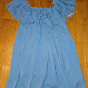  klänning  - Supersöt ljusblå klänning från SHEIN med volang upptill och knytning framtill. Klänningen är kort och har en luftig passform, perfekt för varma dagar. Tillverkad i lätt polyester som ger ett fint fall.