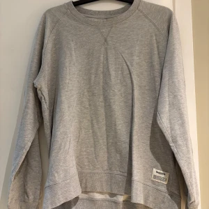 Grå sweatshirt från Resteröds XL - En stilren grå sweatshirt från Resteröds i storlek XL. Tröjan har rund halsringning, långa ärmar och ribbade muddar. Tillverkad i mjuk bomull, perfekt för en chill och avslappnad look. Diskret logga nertill på framsidan.