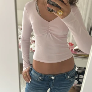Ljusrosa långärmad topp Gina Tricot - Supersöt ljusrosa långärmad topp från Gina Tricot med v-ringning och snygg rynkdetalj framtill. Modellen är figurnära och croppad, perfekt till jeans eller yoga pants. Mjuk och stretchig bomullskvalitet som känns skön mot huden. Använd ganska mycket men har noll defekter, luktar och känns fräsch 💗💞🙌original pris ca 300kr