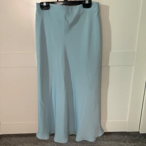 Ljusblå satin midikjol från Bik Bok - Snygga ljusblå satin midikjol från Bik Bok i en flowy stil. Du kan välja om du vill ha den högmidjat ellet lågmidjat. Perfekta för en stilren outfit.