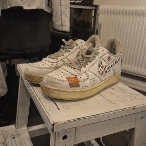 Nike sneakers med 'Just Do It' design - Unika vita Nike sneakers med 'Just Do It' tryck över hela skon. Skorna har en vintage look med gulnade sulor och detaljer i orange. Perfekta för den som vill sticka ut med en klassisk men ändå iögonfallande design. Ska se ut som att dom är lite beat up