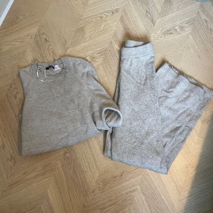Beiget stickad sett från ginatricot - Mysig beige stickad tröja och byxor från Ginatricot med rund halsringning och ribbade muddar vid ärmslut och nederkant. Perfekt för kyliga dagar och ger en avslappnad look.