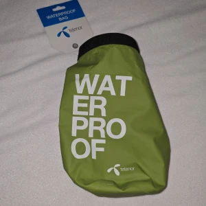 Grön vattentät väska från Telenor - Säljer en grön vattentät väska från Telenor. Perfekt för att hålla dina saker torra. Väskan har en praktisk stängning med spänne och är lätt att bära med sig. Idealisk för utomhusaktiviteter där du behöver skydda dina tillhörigheter mot vatten.