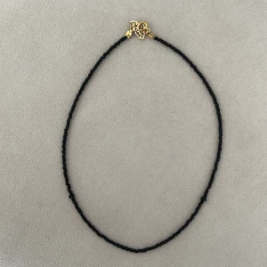 Svart pärlhalsband - Elegant svart pärlhalsband med små pärlor och guldfärgat lås. Perfekt för att ge en stilren touch till din outfit.
