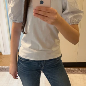 Blå topp med puffärmar från H&M - Säljer en söt blå topp från H&M med puffiga kortärmar. Perfekt för en stilren look. Toppen är i en mjuk och bekväm bomullsmix.