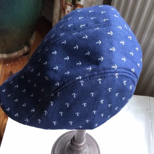 Blå keps med ankarmönster - Snygg blå keps med ett stilrent ankarmönster i vitt. Perfekt för en maritim look. Kepsen har en klassisk form och är tillverkad i ett bekvämt material.