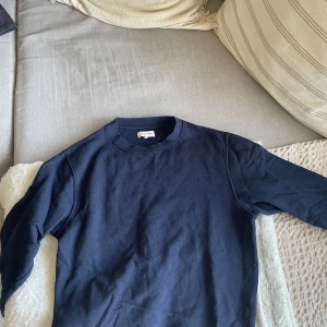 Mörkblå tröja från Studio Total - Säljer en stilren mörkblå tröja från Studio Total. Tröjan har en klassisk rund halsringning och långa ärmar. Perfekt för en avslappnad look.