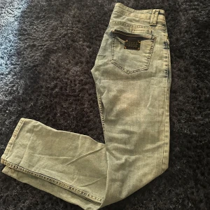 Blå jeans från Philipp Plein - Snygga blå jeans från Philipp Plein med slitna detaljer och en cool knapp med logotyp. De har en klassisk femficksdesign och en orange insida i midjan som ger en extra touch. Perfekta för en trendig look! För mer bilder / frågor hör av er ! 