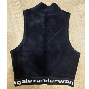 topp från Alexander Wang - Snygg svart  topp från Alexander Wang i mjukt material. Toppen har en hög krage och ett elastiskt band med logotypen längst ner. Perfekt för en stilren look.