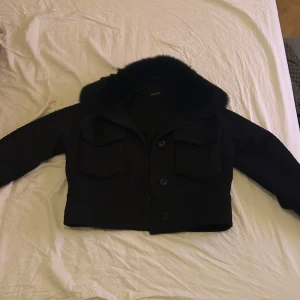 Svart jacka från Meotine - Säljer en stilren svart jacka från Meotine. Jackan har en croppad design med knappar framtill och en mjuk krage. Perfekt för att ge en elegant touch till din outfit.