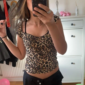 Leopardmönstrad kortärmad topp - Säljer en snygg leopardmönstrad topp med korta ärmar och v-ringning. Perfekt för att ge din outfit en djärv touch. Passar bra till både jeans och kjol.