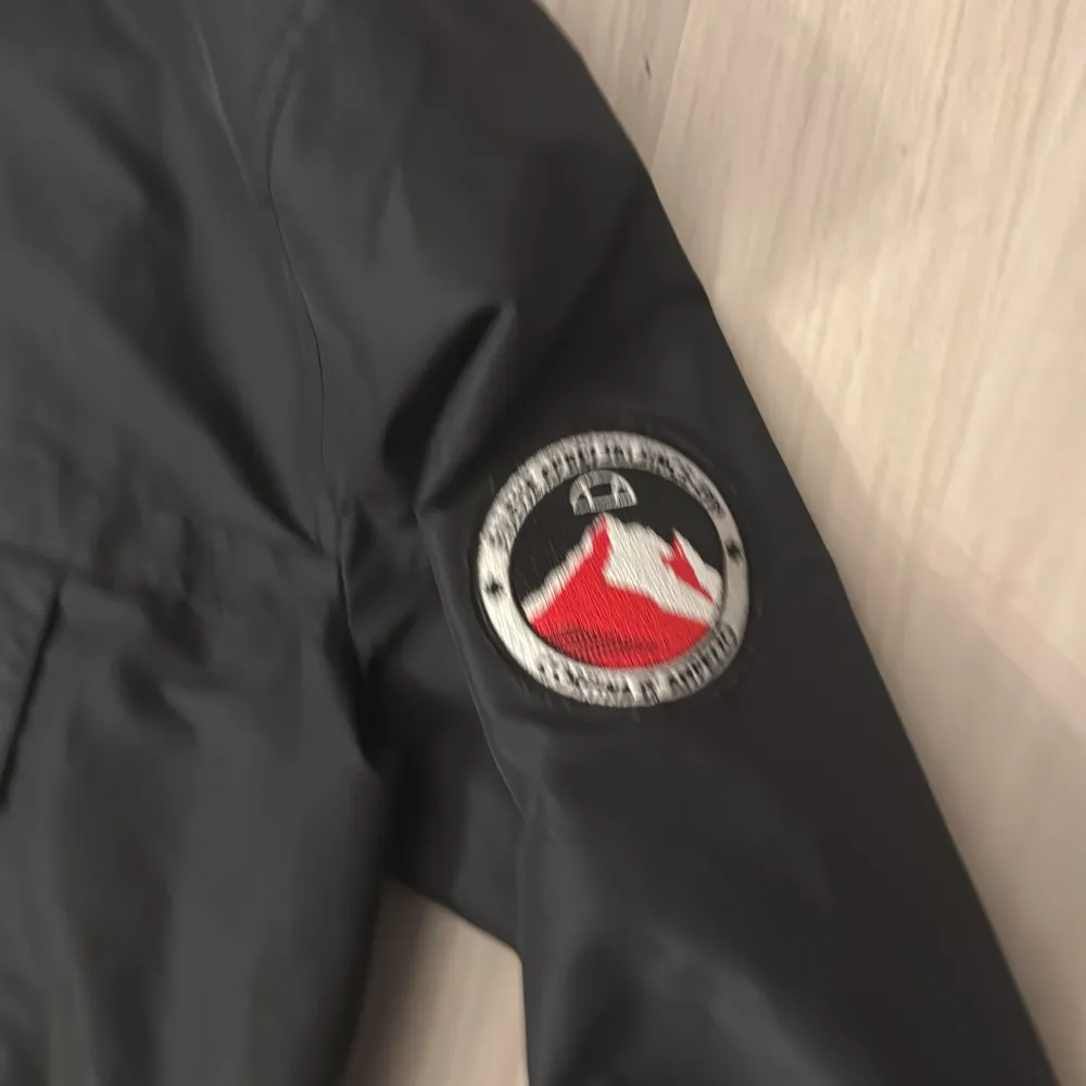Säljer en svart vindjacka från Ellesse med stor logga på bröstet och en patch på ärmen. Jackan har en dragkedja vid halsen och en stor ficka framtill. Jacksn är använd fåtals gånger original pris 1299kr. Takit.