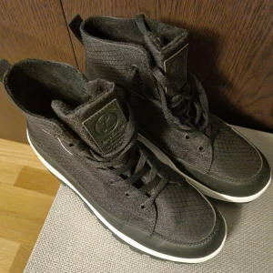 Svarta sneakers med quiltad yta - Svarta skor med quiltad yta och vit sula. Skorna har snörning och en robust sula för bra grepp. 