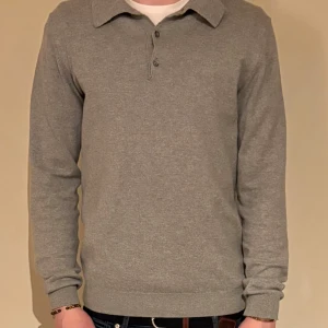Grå långärmad pikétröja från Martinique europé  - Säljer en stilren grå långärmad pikétröja från Martinique. Tröjan har en klassisk krage och knappar framtill. Perfekt för en avslappnad men ändå uppklädd look.