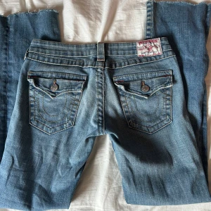 Blå jeans från True Religion - Säljer ett par klassiska blå jeans från True Religion. De har snygga bakfickor med knappar och en dragkedja fram. Perfekta för en avslappnad stil.det är straight men går lätt att ny som till bootcut om man vill de