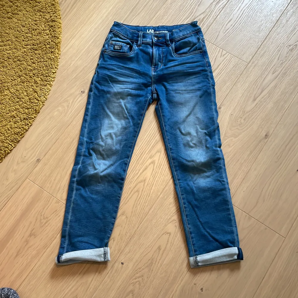 Bundle av fyra jeans som även går att köpa enskilt. Två par jeans från Lindex i storlek 140/9-10Y. Passformen är slim och modellnamnet är Staffan. Ena paret är grått och det andra är blått. Två par av jeans från LAB Industries där båda är relaxed fit, ena paret är storlek 134 och det andra är 140. Storlek 140 har svarta detaljer och 134 har bruna detaljer. . Farkut & Housut.